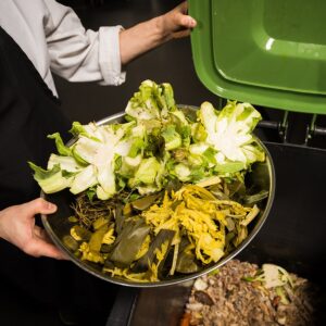 Chef emptying vegetable scraps into a composting bin